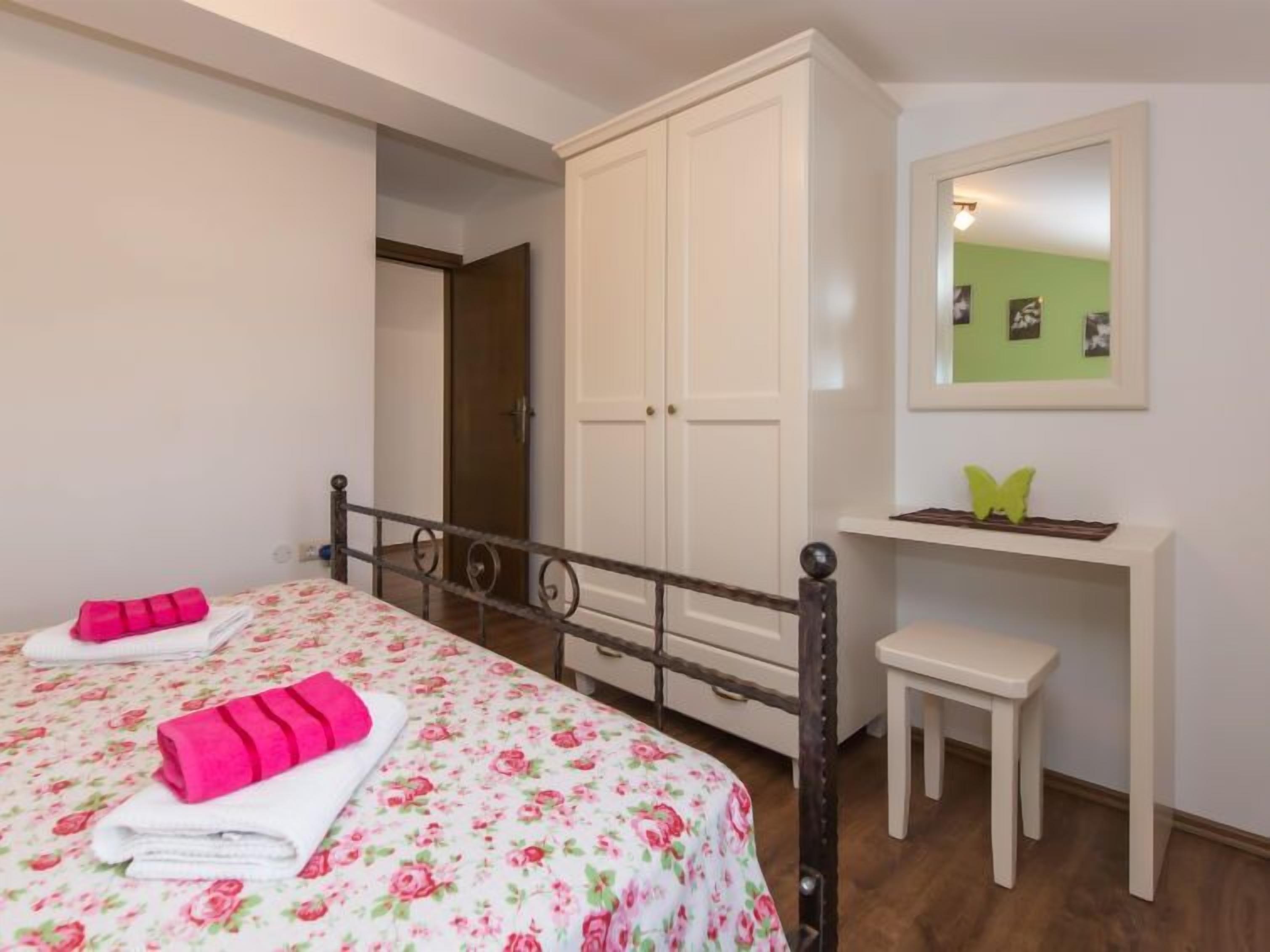Une chambre à coucher avec un lit, deux tables de chevet, une armoire et un miroir au mur.