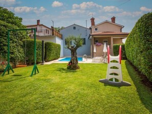 A residential property with a swimming pool, a swing set, and a well-maintained lawn. - Vacation home Cvitan by Interhome (Tinjan)