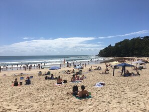 A beach with people sunbathing, umbrellas, and beach chairs. - Close to beach at Sunrise (Sunrise Beach)