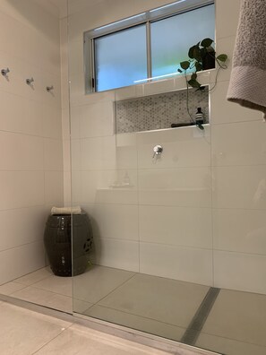 Un bany modern amb un immoble de banyera de vidre, una petita finestra i un penjador de tovalloles.