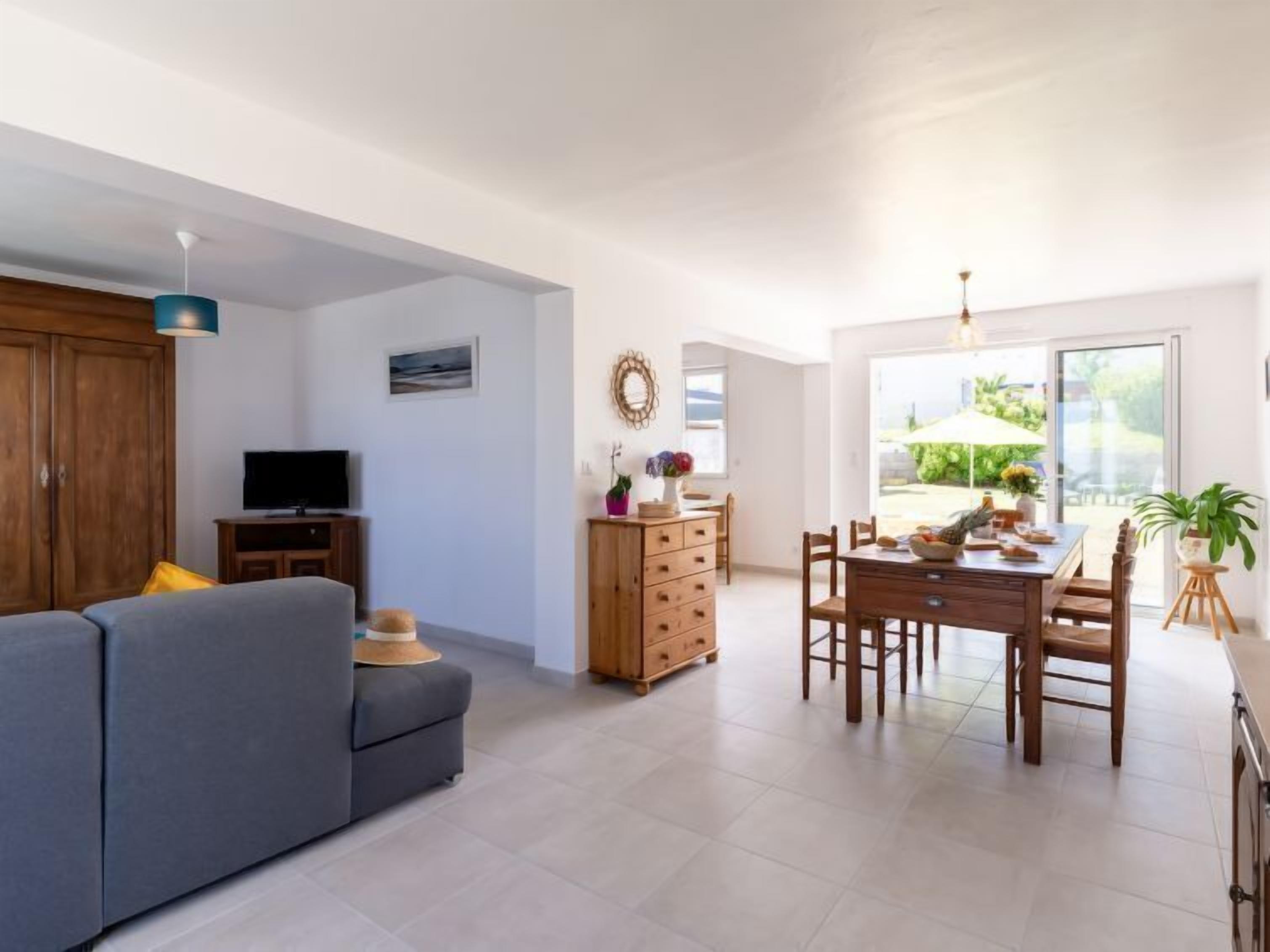 A modern living room with a sofa, TV, wooden cabinet, and a dining area with a table and chairs.