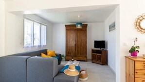 A modern living room with a grey sofa, wooden cabinet, and a television on a wooden stand. - l'Emeraude by Interhome (Saint Cast le Guildo)