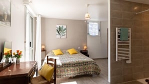 A bedroom with a bed, bedside tables, a chair, a window, and a towel rack. - l'Emeraude by Interhome (Saint Cast le Guildo)