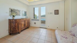 A room with a wooden cabinet, a sofa, a ceiling with skylights, and a door leading to a balcony. - Lambrusca by Interhome (Moneglia)