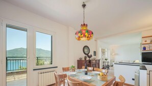 A dining area with a table set for four, a chandelier, and a view of the sea through large windows. - Lambrusca by Interhome (Moneglia)