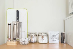 Una encimera de cocina con diversos utensilios, como un cuchillo, saleros y pimenteros, y un molinillo de café.