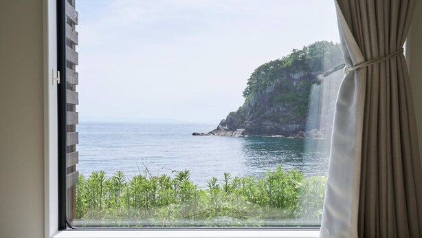 Una ventana con vistas a un paisaje costero, que incluye un acantilado y el mar.
