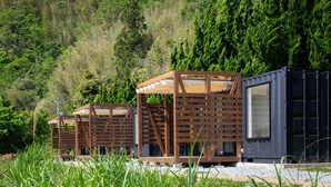 Una cabaña moderna con fachada de madera y ventanas amplias, rodeada de vegetación exuberante.