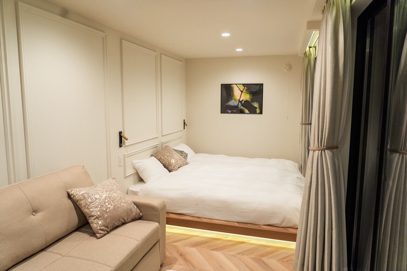 A bedroom with a bed, a sofa, and a painting on the wall.