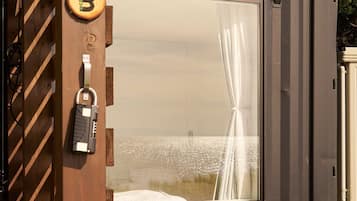 A room with a large window, a bed, and a door with a key lock.