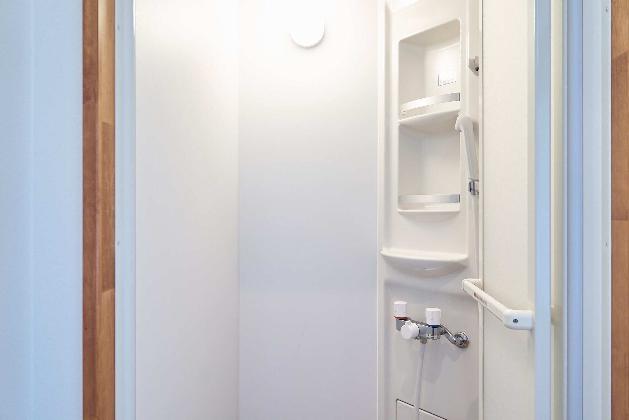 Een badkamer met een witte deur, een handdoekhouder en een zeepdispenser.