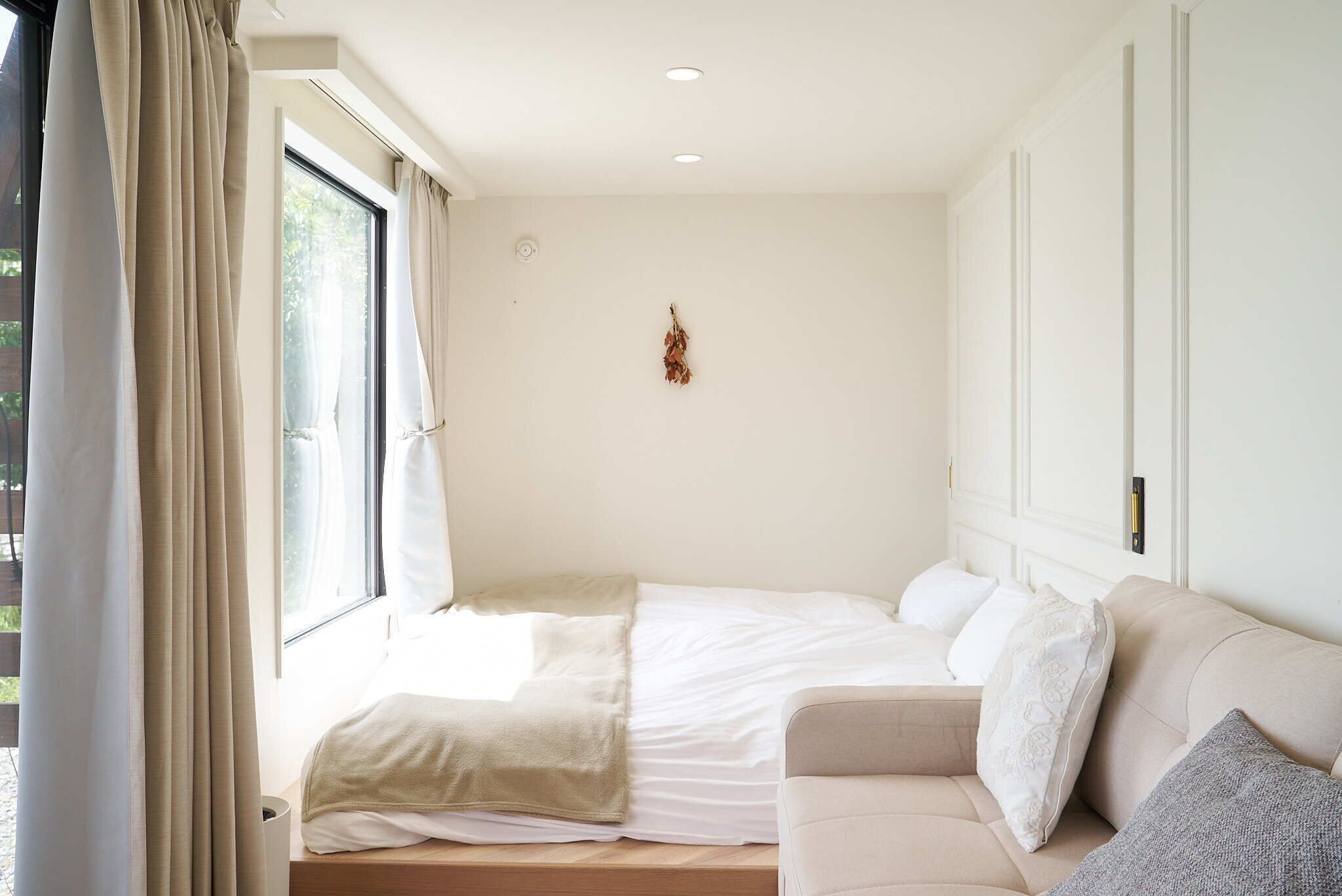 A bedroom with a bed, a sofa, and a window with curtains.