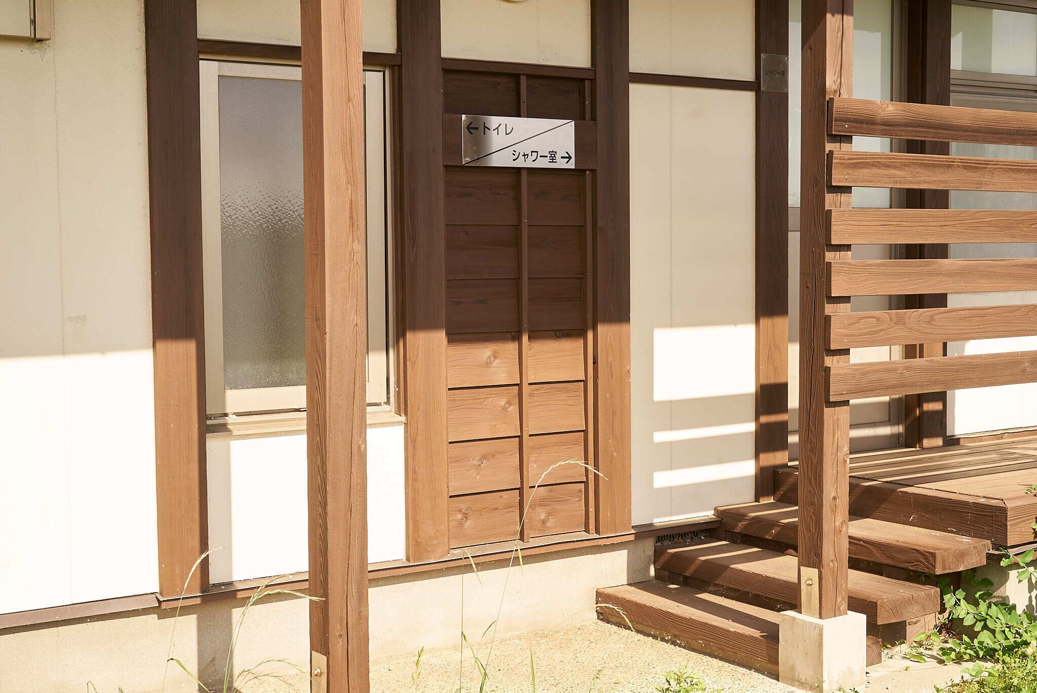 A wooden staircase leading to a door with a sign indicating directions to the lobby and a room.