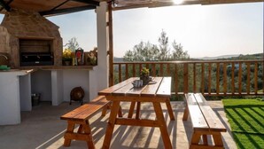 An outdoor patio with a stone oven, wooden table, and benches. - La Pedriza by Interhome (Cordoba/Rute)