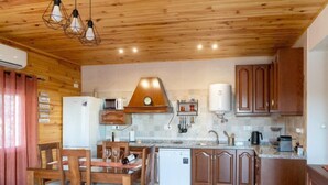 A modern kitchen with wooden cabinets, a built-in oven, and a dining area with a wooden table and chairs. - La Pedriza by Interhome (Cordoba/Rute)