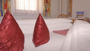 Een hotelkamer met een bed, kussens, een stoel, een tafel en een spiegel.