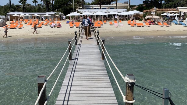 A wooden pier leading to a beach with orange lounge chairs and umbrellas. - 2 BEDROOM HOUSE IN PORT COGOLIN (with pontoon for boat) (PORT COGOLIN)