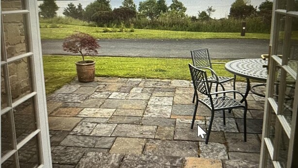 Un patio al aire libre con suelo de piedra, una planta en maceta y una mesa con sillas.