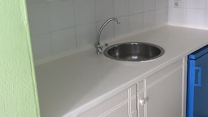A kitchen with white cabinets, a stainless steel sink, and a blue cabinet. - Hotel Asimina (Zakynthos)