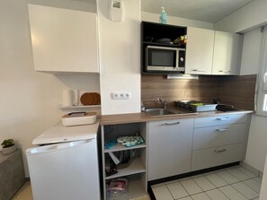Cocina compacta con microondas, lavamanos y armarios de almacenamiento.