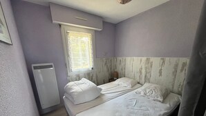 A bedroom with a bed, a window, a heater, and a wall-mounted light fixture.