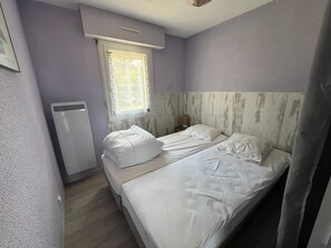 Una camera da letto con un letto, una finestra, un termosifone e un punto luce a parete.