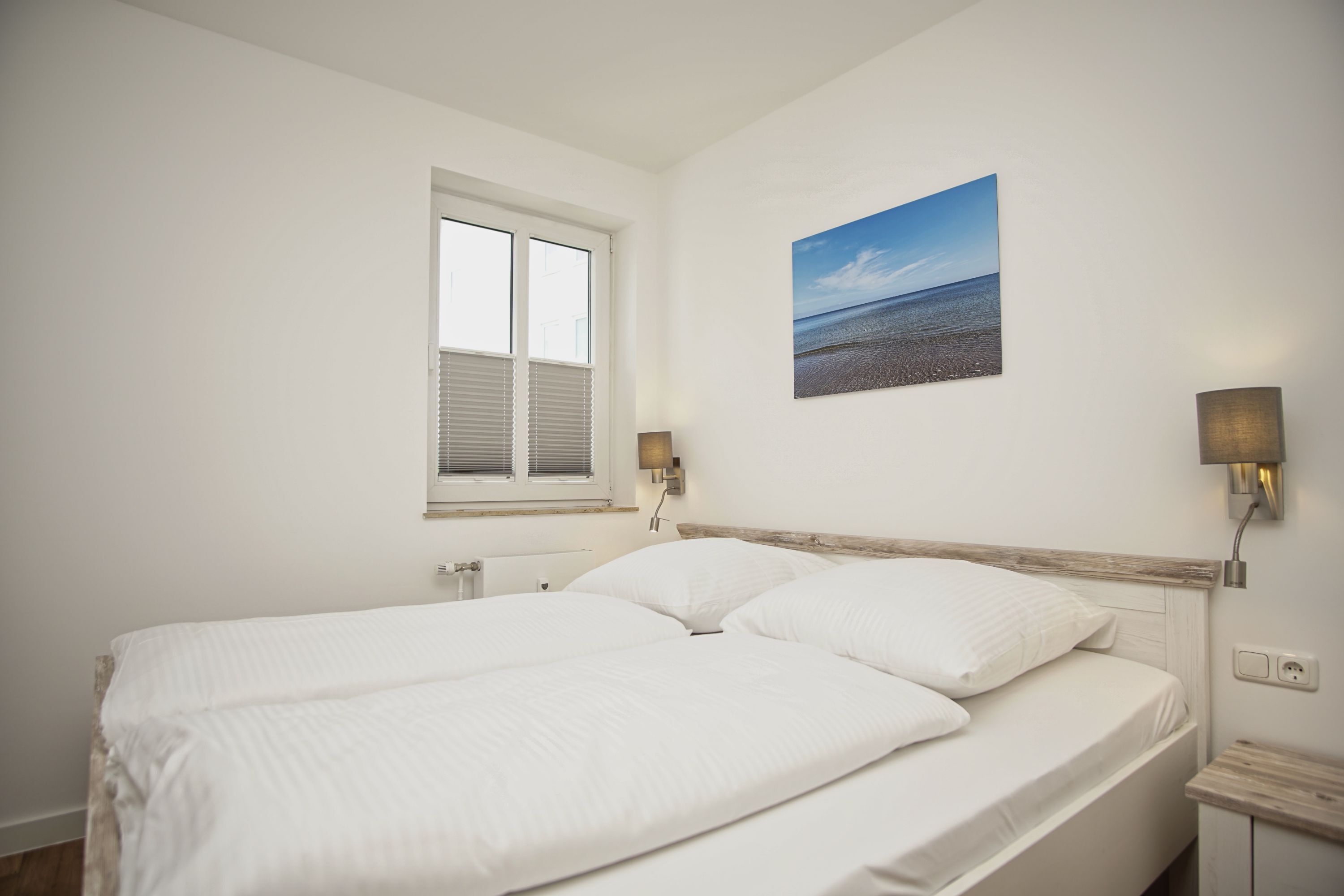 Une chambre avec un grand lit, une fenêtre et un tableau accroché au mur.