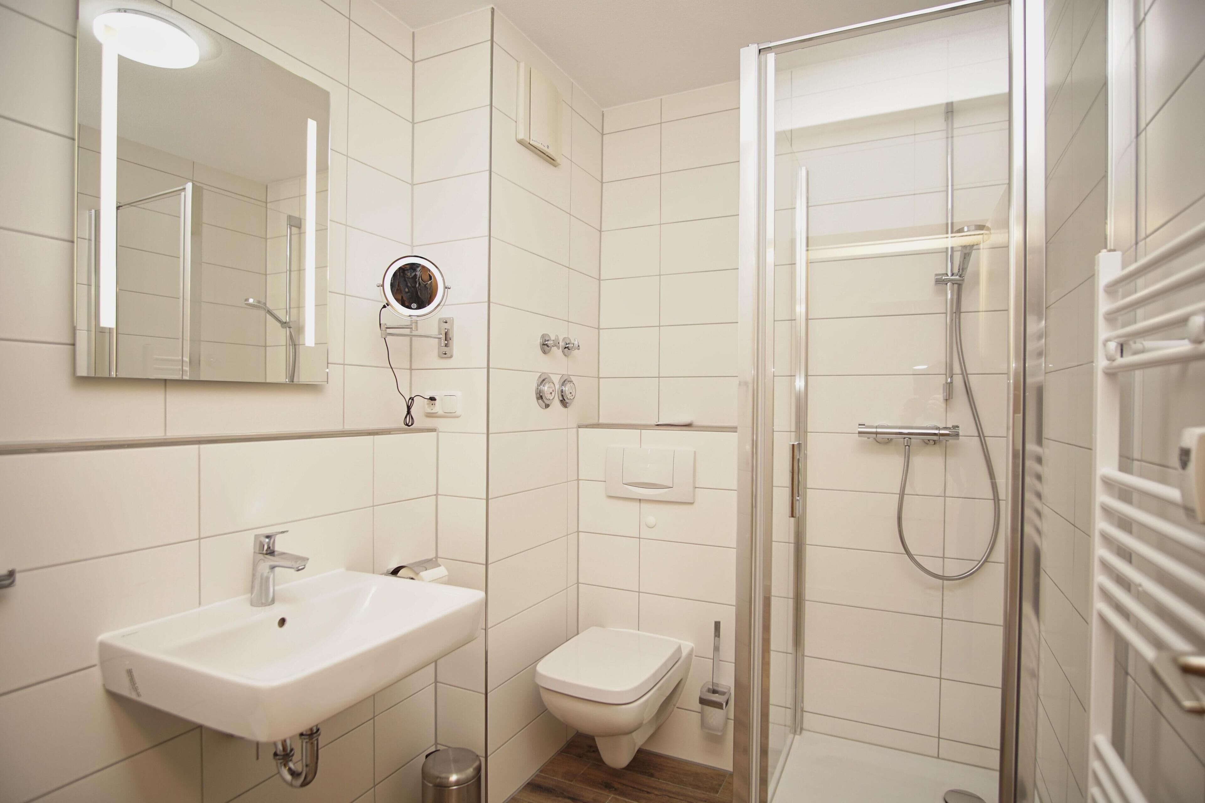 Ein modernes Badezimmer mit Waschbecken, Toilette und einer Duschkabine.