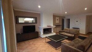 A living room with a fireplace, a television, a sofa, and a coffee table. - Villa Avec Apercu MER ET Piscine Privee (Sainte-Maxime)