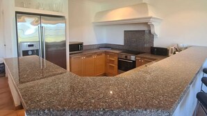 A modern kitchen with granite countertops, stainless steel appliances, and wooden cabinets. - Villa Avec Apercu MER ET Piscine Privee (Sainte-Maxime)