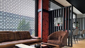 A modern living room with a sofa, a coffee table, and a chair. There is a decorative wall with a geometric pattern and a red accent wall. - World Class Airport Hotel (Arnavutköy)