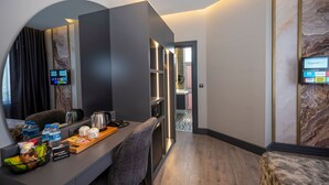 A modern hotel room with a desk, coffee maker, and a digital screen displaying room service options. - World Class Airport Hotel (Arnavutköy)