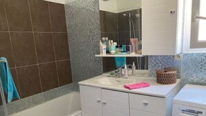 Une salle de bain équipée d’une baignoire, d’un lavabo, d’un miroir et d’un lave-linge.