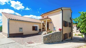 Un edificio a due piani con tetto in tegole, una scalinata in pietra e un'area d'ingresso pavimentata.