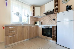 Une cuisine avec des meubles en bois, un four à micro-ondes, un four traditionnel et un réfrigérateur.