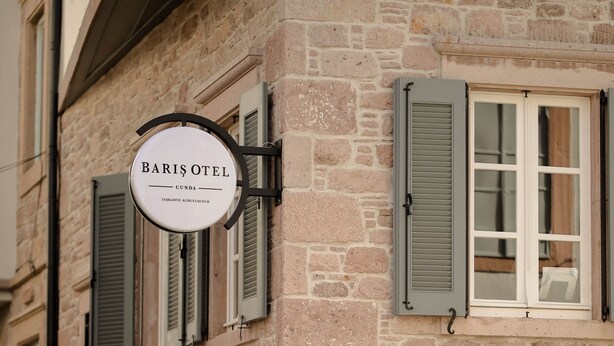 Un bâtiment en pierre avec une enseigne indiquant « BARIOTEL CUNDA » et des volets aux fenêtres.