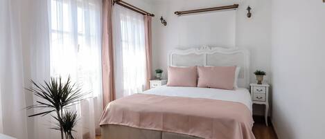 A bedroom with a bed, bedside tables, a potted plant, and a chandelier.