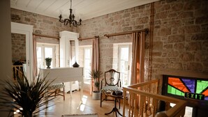 Un salon spacieux avec un piano, un escalier et une vue sur l’extérieur.