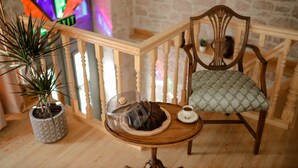 Une pièce chaleureuse avec une chaise en bois, une petite table sur laquelle se trouve une théière et une plante en pot.