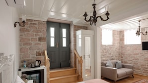Une chambre à coucher comprenant un lit, une commode, une table de chevet, une cheminée, un canapé, un escalier et un mur en pierre.