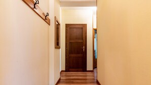 Un couloir avec une porte en bois, un porte-manteau et un tableau encadré accroché au mur.