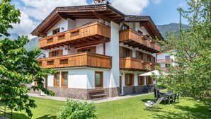 Un immeuble à plusieurs étages, doté de balcons en bois, d’une base en pierre et d’une cour verdoyante.