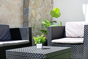 A wicker outdoor seating area with a potted plant on a square table.