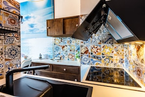 A kitchen with a tiled backsplash, a wooden cabinet, and a black countertop.