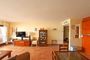 A living room with a television, a cabinet, a chair, and a table. - Holiday Apartment 'Casita Dorada Cala d'Or' near Beach with Pool & Wi-Fi (Cala D'or)