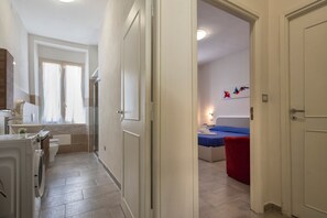 Une chambre d’hôtel avec salle de bain, un lit et un petit coin salon.