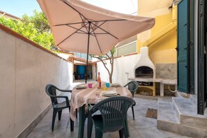 Une terrasse extérieure avec une table, des chaises et un four à pizza.