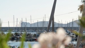 A marina with numerous boats docked, a clear sky, and mountains in the background. - Apartment Casa Vacanza Soffio with Terrace, A/C & Wi-Fi (alghero)