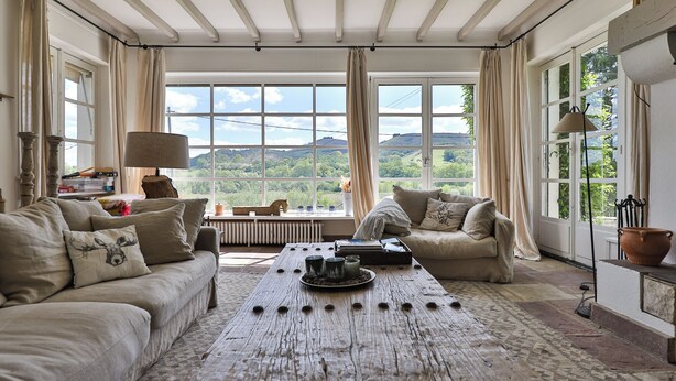 Ein gemütliches Wohnzimmer mit großem Fenster, einem Holztisch und zwei Sofas.