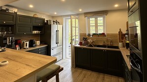 Eine moderne Küche mit dunklen Schränken, einer Holzausziehtafel und einer großen Kochinsel mit Barhocker.